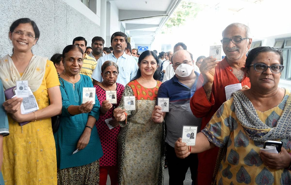 Voters show their Election Commission IDs before they cast their ballot during the polling day for the Karnataka Assembly election. PTI photo