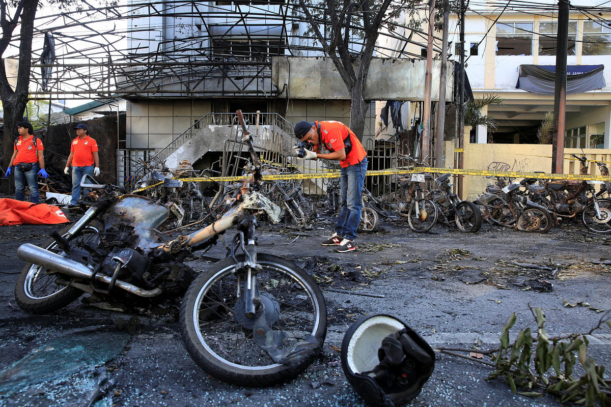 A forensic police officer takes pictures of debris near burned motorcycles following a blast at the Pentecost Church Central Surabaya (GPPS), in Surabaya. Reuters file photo