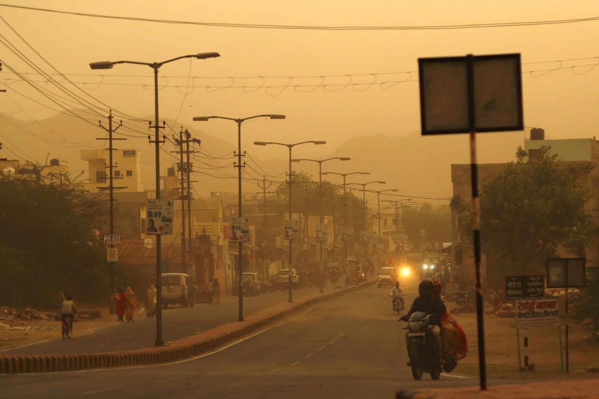 Commuters travel along a road during a heavy dust storm in Ajmer, Rajasthan, on Monday. AFP