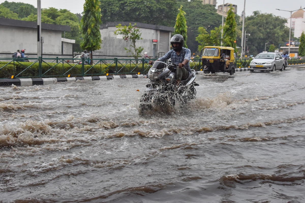 Motorist struggle to ride vehicles in stagnanted Rain water opp Cubbon Park Metro station, Cubbon Road in Bengaluru on Monday. Photo by S K Dinesh