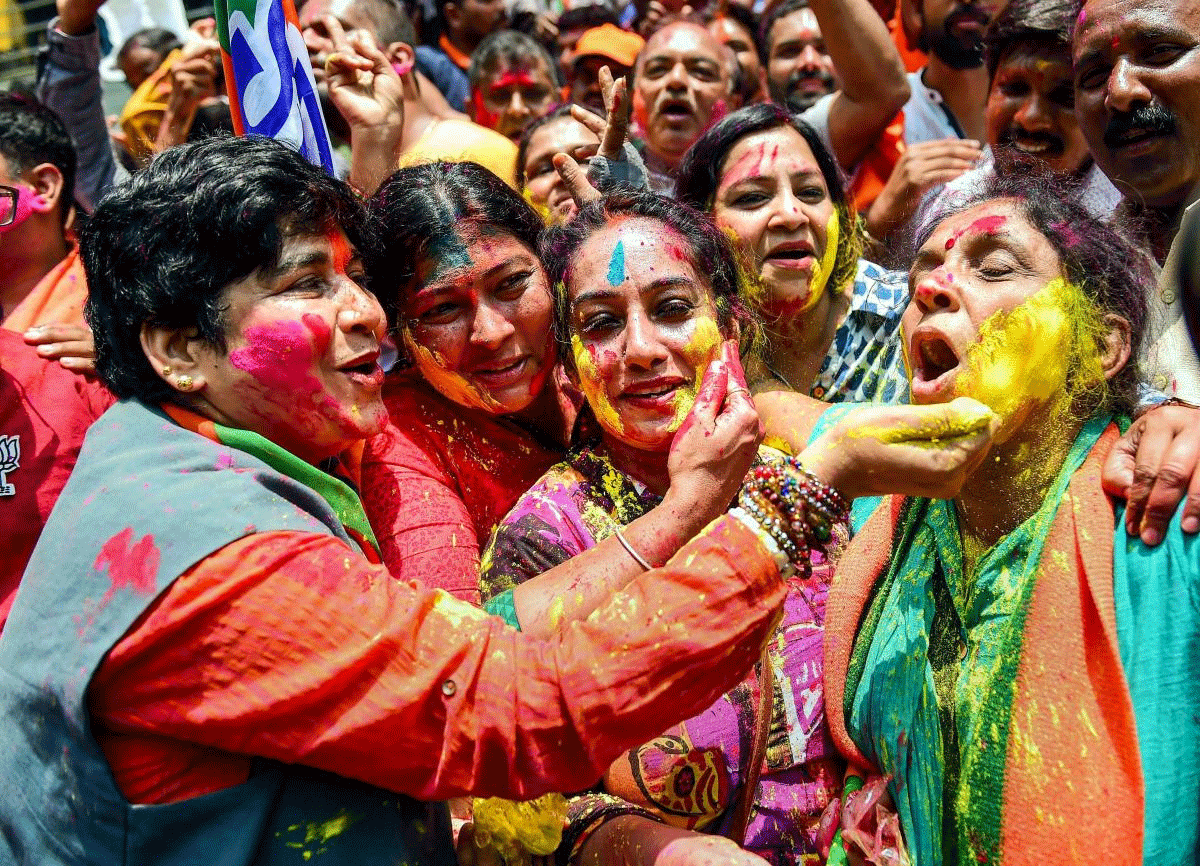BJP workers celebrate with colours the party's lead on more than 110 Assembly seats, as the counting of votes is in progress, outside the party office in Bengaluru on Tuesday. PTI Photo 