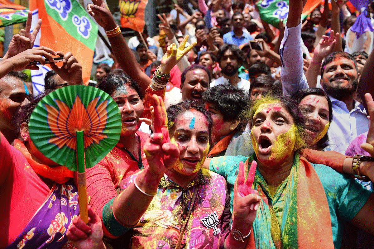 BJP workers celebrate with colours the party's lead on more than 110 Assembly seats, as the counting of votes is in progress, outside the party office in Bengaluru on Tuesday. PTI Photo