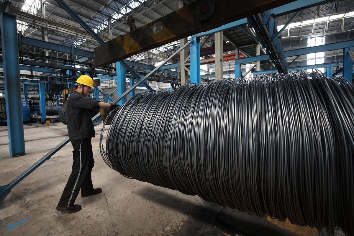 (FILES) This file photo taken on May 1, 2018 shows a worker handling steel cable at a steel factory. AFP
