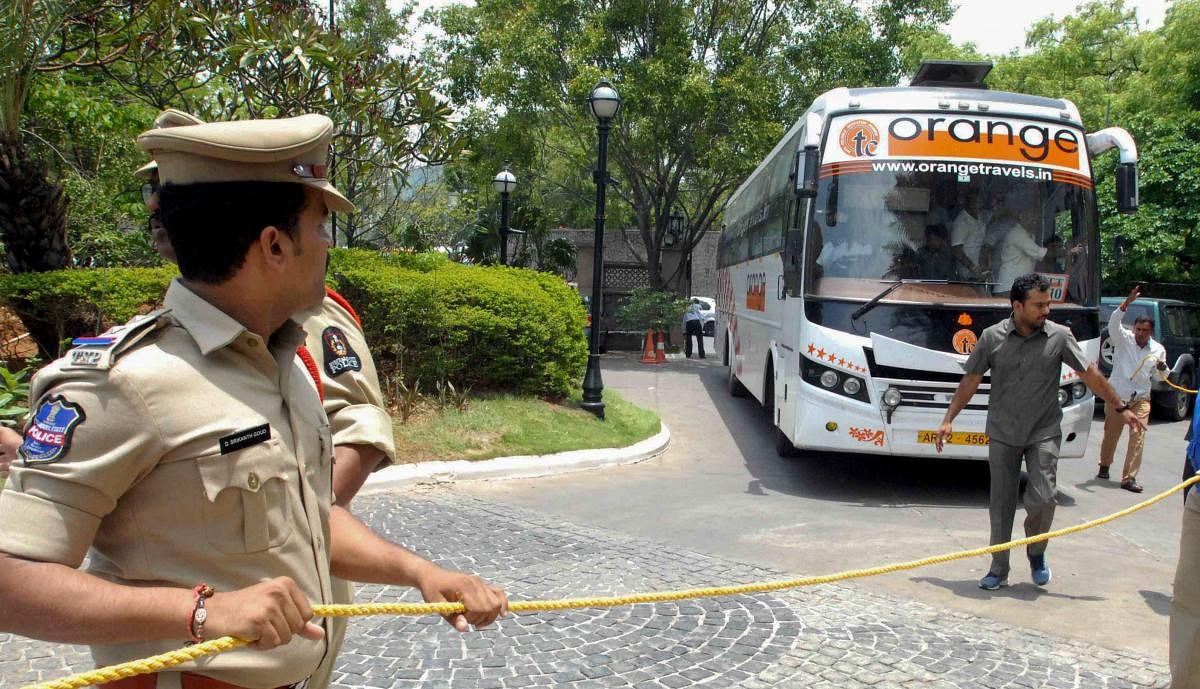 A poiceman looks on as Karnataka Congress and JD(S) MLAs arrive in a bus at Taj Krishna Hotel, in Hyderabad, on Friday. (PTI Photo)