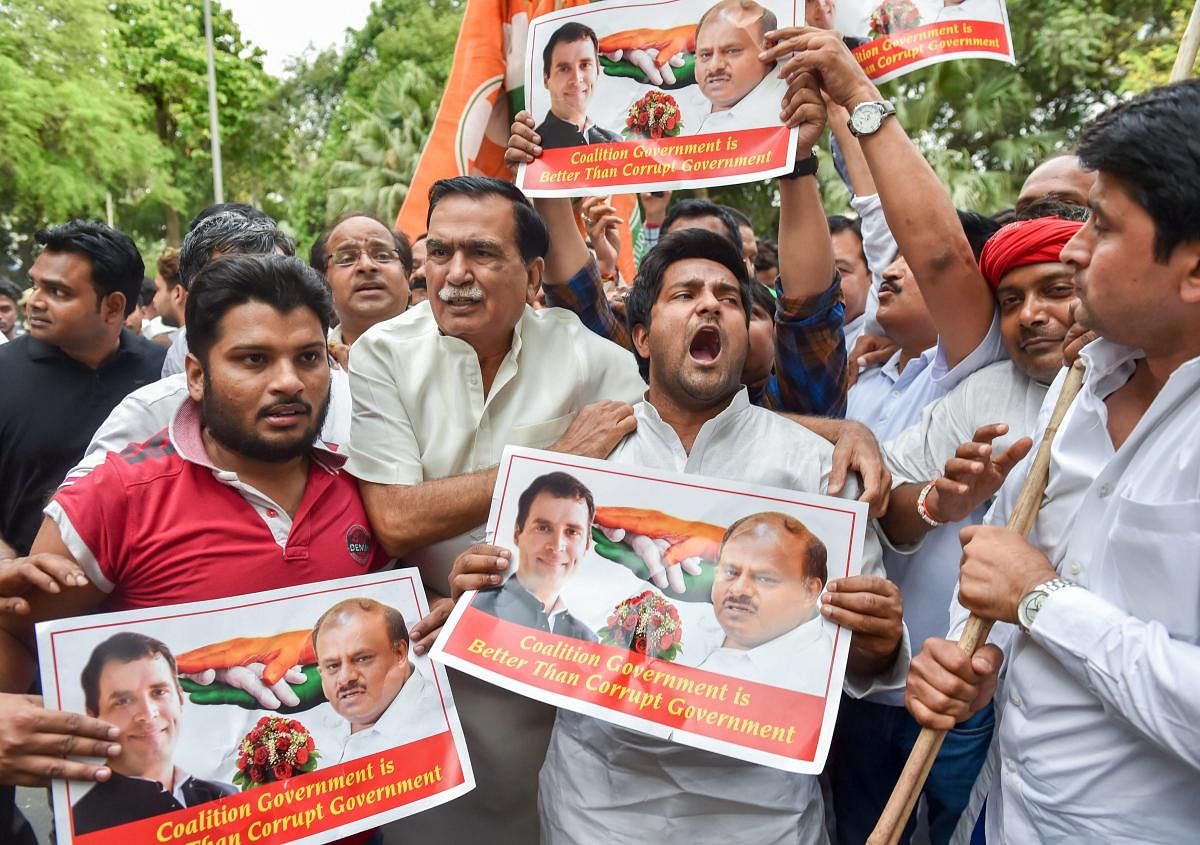 Congress party workers celebrate with posters of party President Rahul Gandhi and JD(S) chief HD Kumarswamy after Karnataka Chief Minister BS Yeddyurappa announced his resignation, in New Delhi on Saturday. PTI Photo