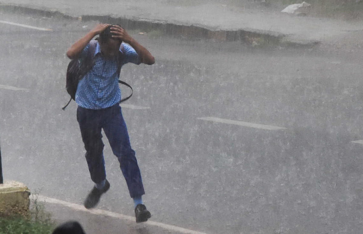 A boy running during sudden rain at Ramavilas Road in Mysuru on Friday. -Photo by Savitha. B R