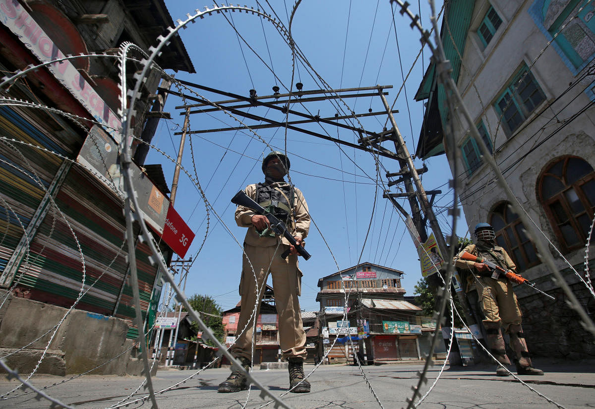 Indian policemen stand guard behind concertina wire during a strike called by separatists to mark the death anniversaries of chief cleric of Kashmir, Moulana Mohammad Farooq and Abdul Gani Lone, a Kashmiri separatist leader, in Srinagar May 21, 2018. REUTERS/Danish Ismail