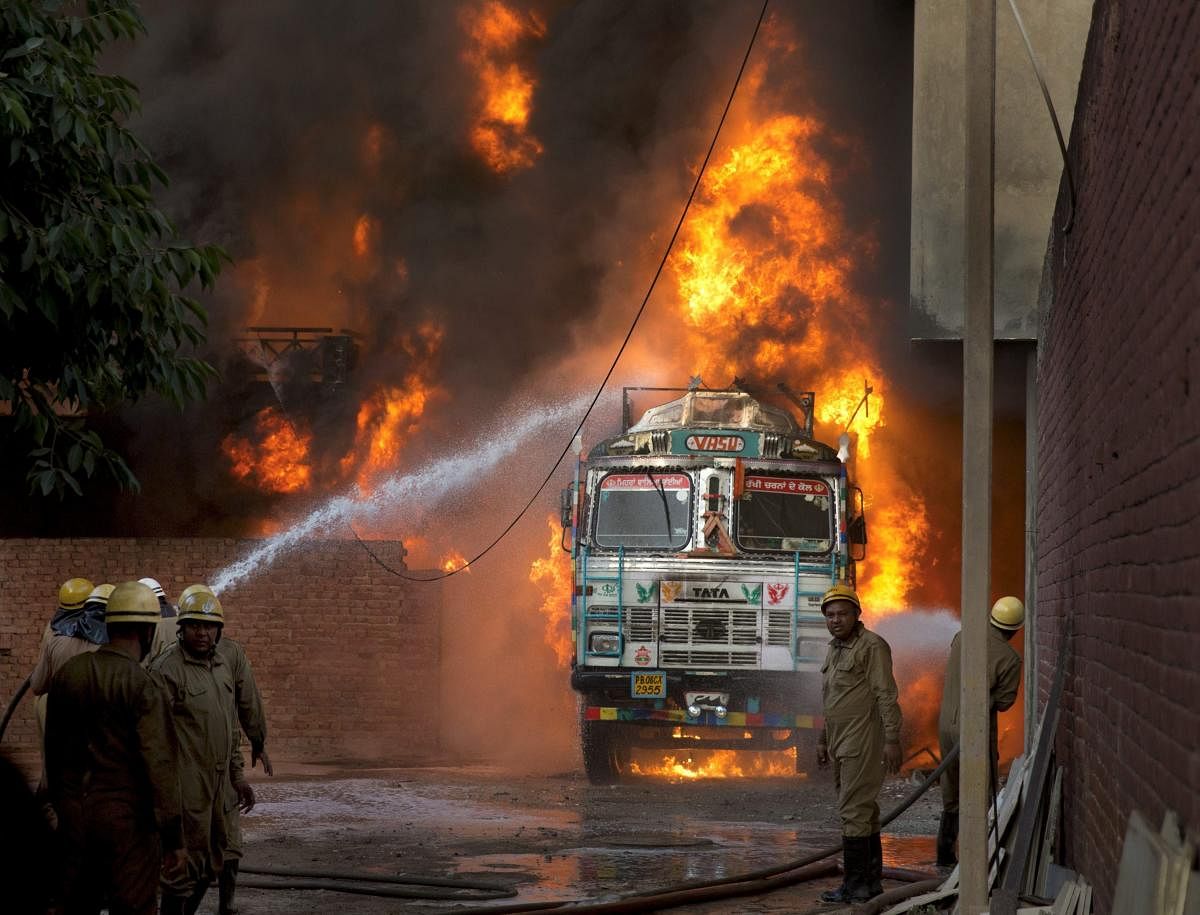 Firefighters douse flames on a truck which caught fire at Malviya Nagar in New Delhi, on Tuesday, May 29, 2018. The truck fire later spread to a nearby godown. PTI Photo