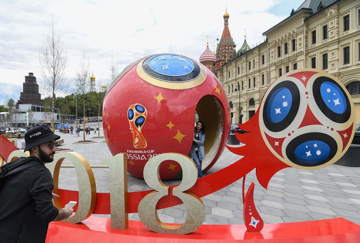 People pose for pictures in front of a 2018 FIFA World Cup decoration at Moscow's Zaryadye Park outside the Kremlin. AFP