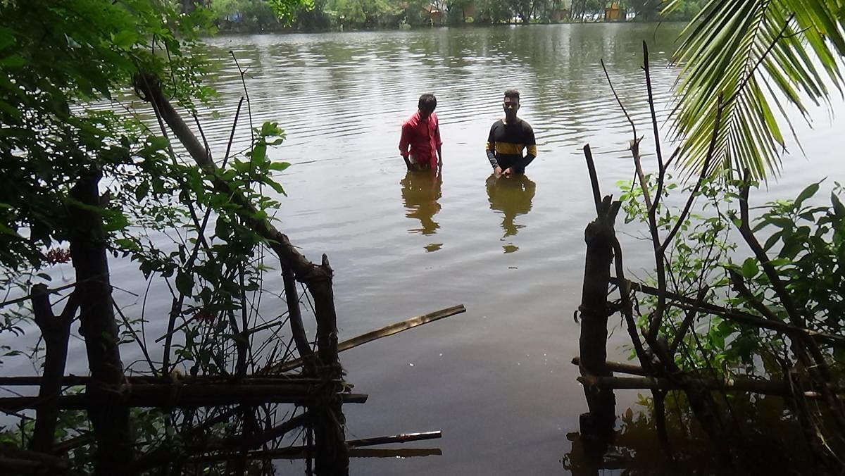 Two youths stand in waist-deep water at Kharviwada village of Ankola taluk, Uttara Kannada district. dh photo