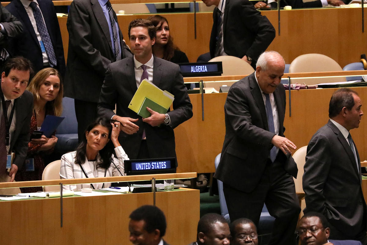 Palestinian Ambassador to the United Nations Riyad Mansour (2nd from R) passes U S Ambassador Nikki Haley (seated L) during a vote on the adoption of a draft resolution by the United Nations General Assembly to deplore the use of excessive force by Israel