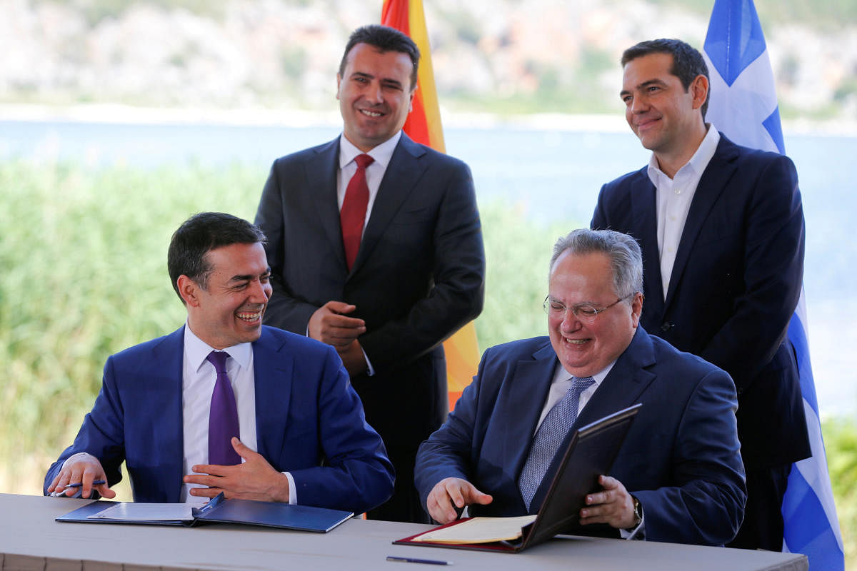 Greek Foreign Minister Nikos Kotzias and his Macedonian counterpart Nikola Dimitrov sign an accord to settle a long dispute over the former Yugoslav republic's name as Greek Prime Minister Alexis Tsipras and Macedonian Prime Minister Zoran Zaev look on in the village of Psarades, in Prespes, Greece, June 17, 2018. Reuters