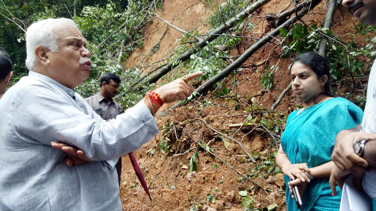Revenue Minister R V Deshpande inspects the landslide on Konanooru-Makutta state highway connecting Kerala, on Monday.