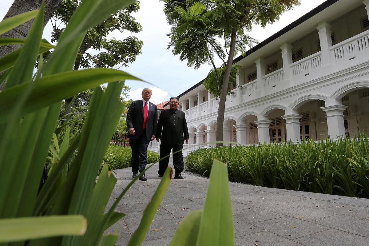 U.S. President Donald Trump and North Korea's leader Kim Jong Un walk together before their working lunch during their summit at the Capella Hotel on the resort island of Sentosa, Singapore June 12, 2018.