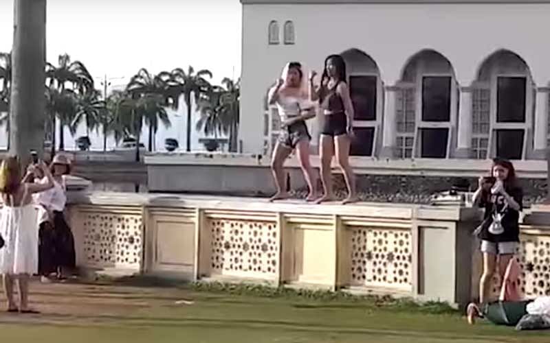 The pair were filmed doing the dance in skimpy shorts and tops exposing their mid-riffs on a wall outside the main mosque in the city of Kota Kinabalu, a popular site for visitors and tour groups. (Secreengrab)