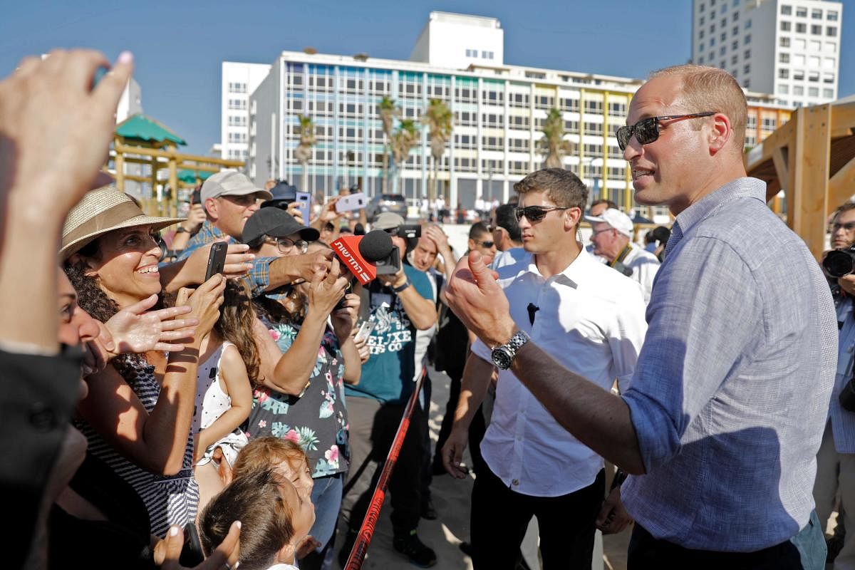 Reporters and beach-goers swarm around Britain's Prince William (right) as he visits a beach in the coastal Israeli Mediterranean city of Tel Aviv on June 26, 2018. AFP
