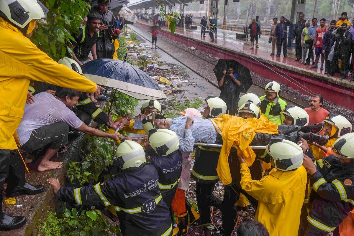 Rescue workers carry an injured for treatments after a foot-overbridge collapsed on the railway tracks following heavy rains, at Andheri Station in Mumbai on Tuesday, July 3, 2018. (PTI Photo)