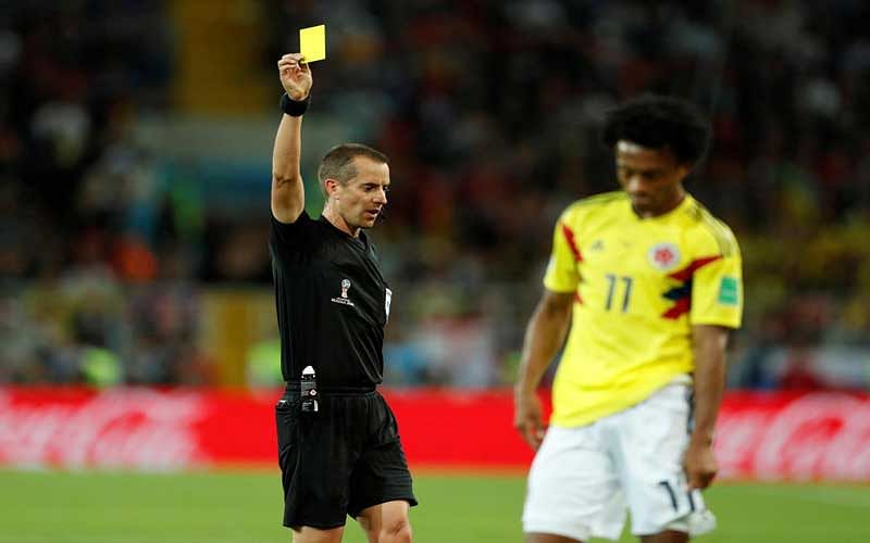 STRUGGLING FOR CONTROL: Referee Mark Geiger (left) brandishes the yellow card to Colombia's Juan Cuadrado. The Colombians, who resorted to rough play, earned six yellow cards in total. (Reuters Photo)