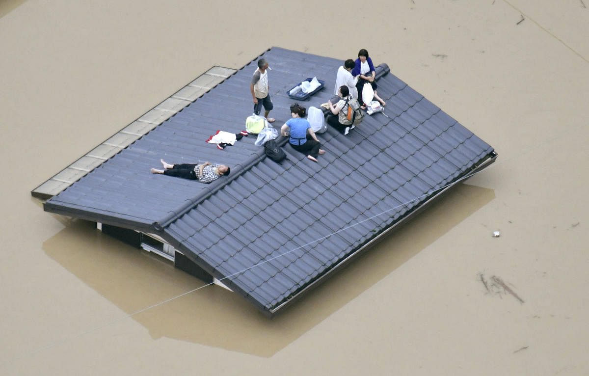 An aerial view shows local residents seen on the roof of a submerged house at a flooded area as they wait for a rescue in Kurashiki, southern Japan. (Reuters Photo)