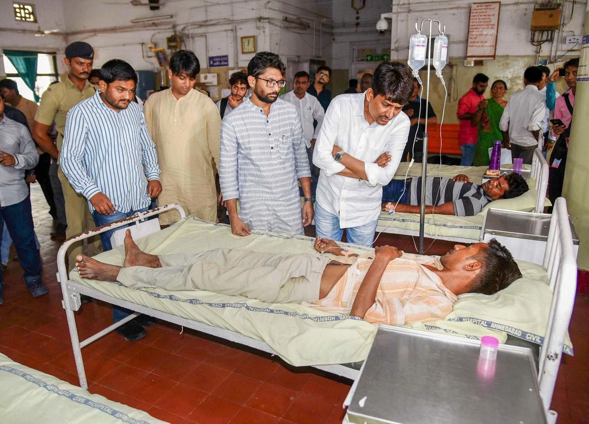 Ahmedabad: Congress MLA Alpesh Thakor, Patidar Anamat Andolan Samiti (PAAS) convenor Hardik Patel with Gujarat MLA Jignesh Mevani interact with people who were hospitalized in a critical condition after drinking country liquor, at a Civil hospital in Ahmedabad on Thursday, July 05, 2018. (PTI Photo)