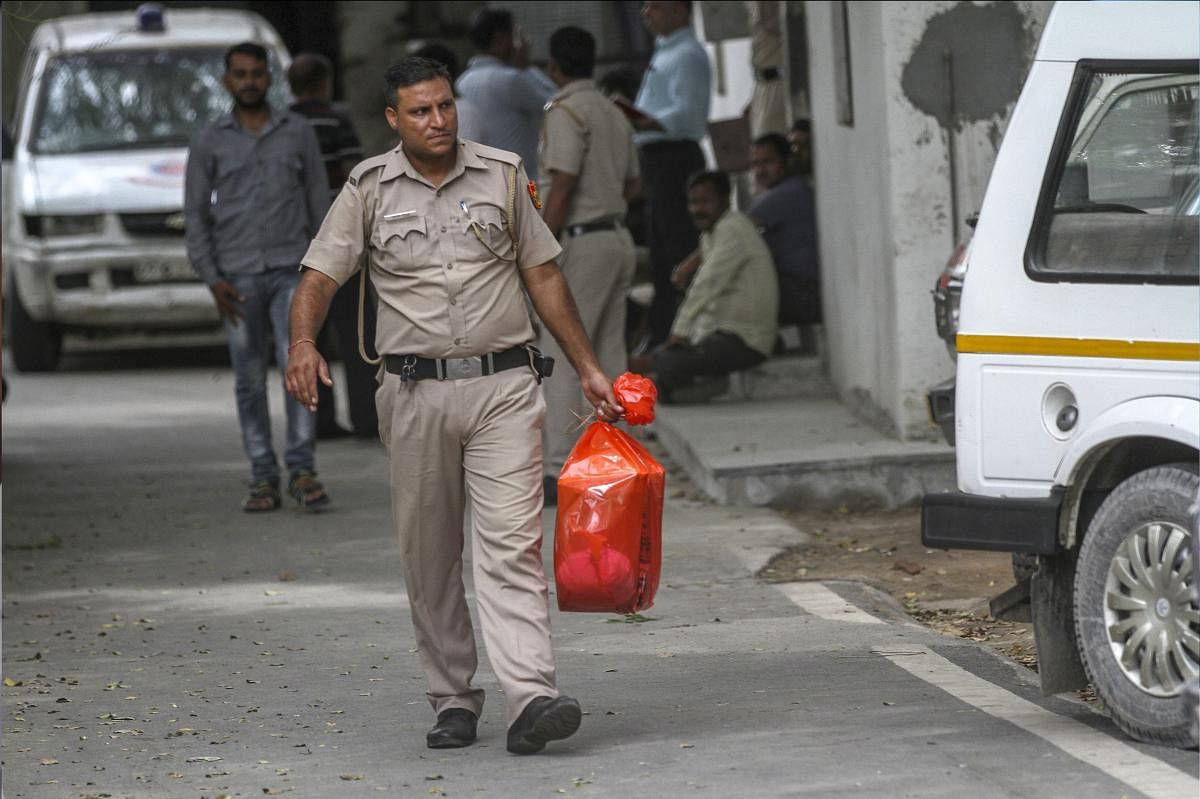 A policeman carries the postmortem reports, of the family of 11 members who were found hanging in their house in Burari, New Delhi. (PTI File Photo)