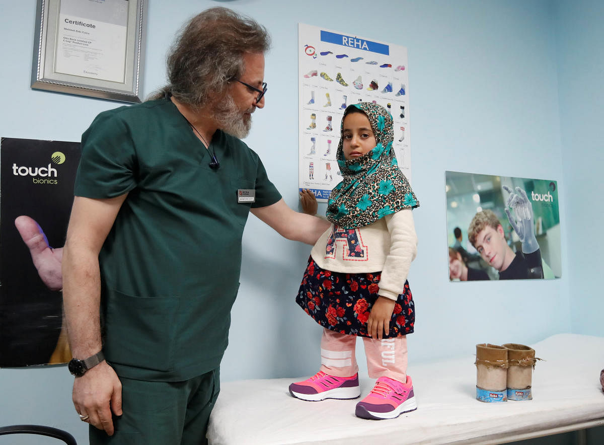 Prosthetics technician Mehmet Zeki Culcu adjusts artificial legs for Maya Meri at a prosthetic center in Istanbul. (Reuters Photo)