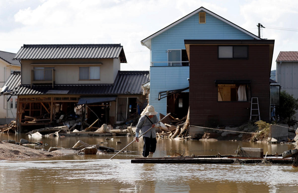 An elderly woman walks next to submerged and destroyed houses in a flooded area in Mabi town in Kurashiki, Okayama Prefecture, Japan. (Reuters Photo)