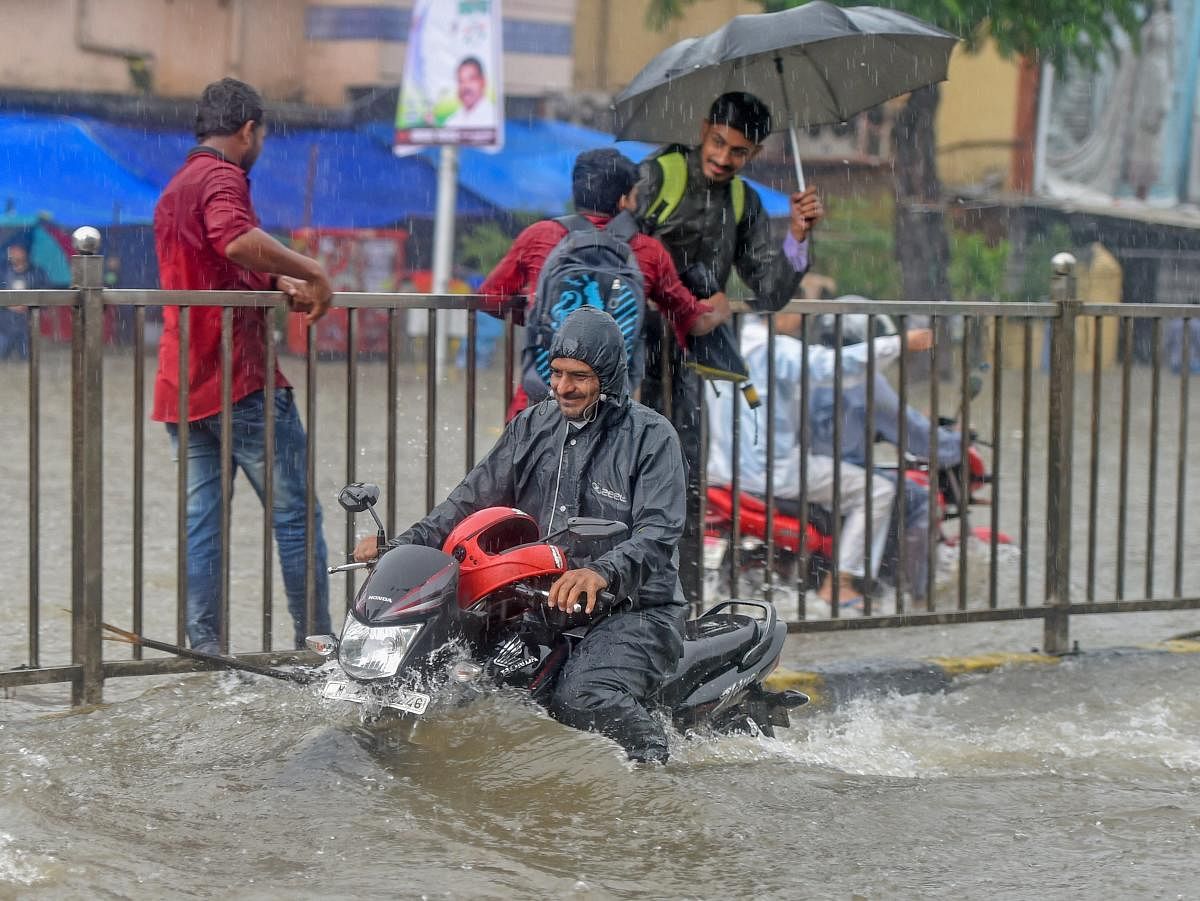 A man rides his motorcycle through a flooded road at King Circle after heavy downpour, in Mumbai on Tuesday, July 10, 2018. PTI Photo