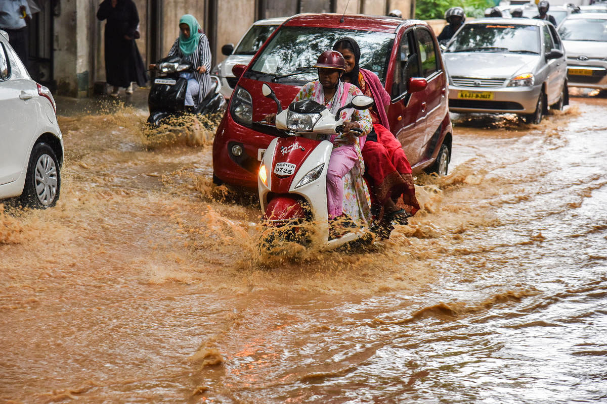 Motorists struggle to navigate a waterlogged Kadidal Manjappa Road near CMP Junction in Bengaluru on Tuesday. dh Photo/S K Dinesh