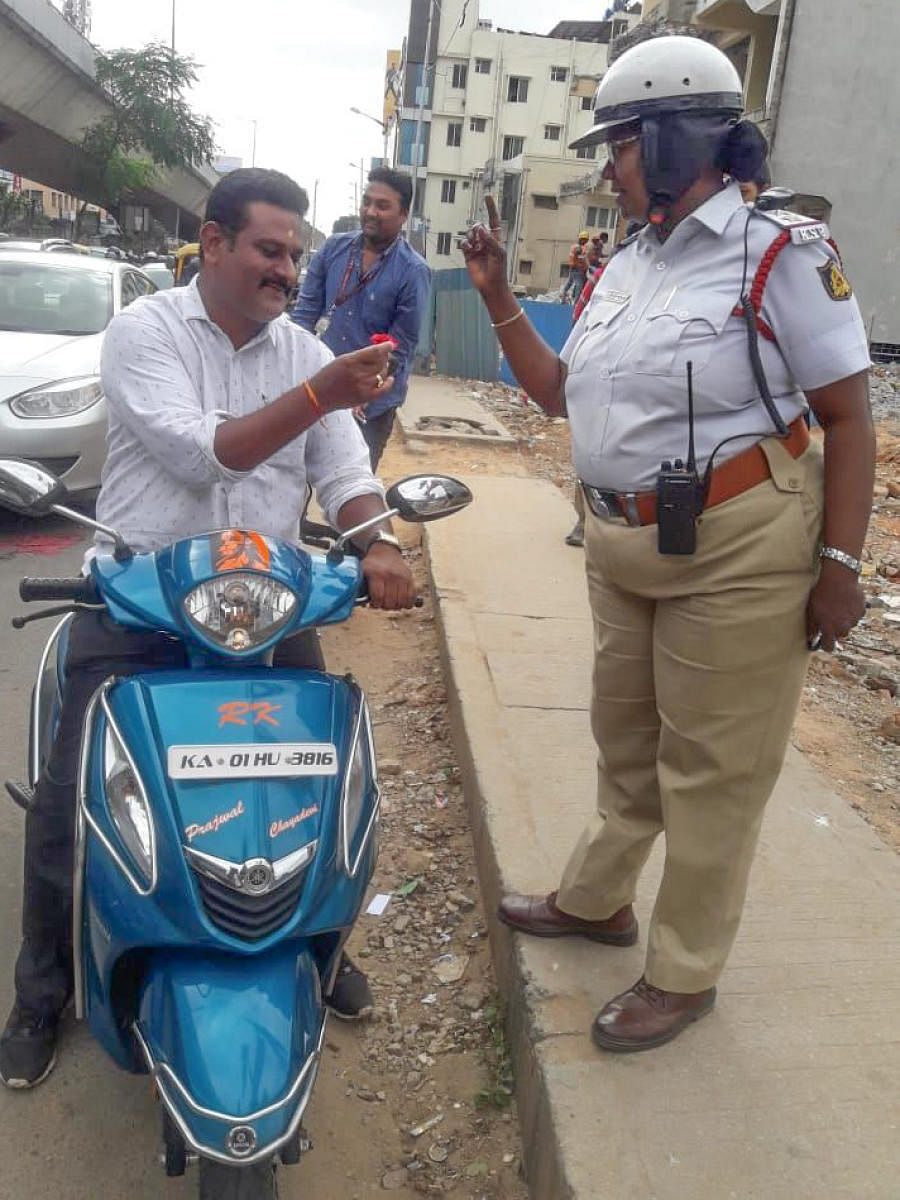 A policewoman hands over a rose to a traffic offender in Mico Layout on Tuesday. DH PhoTO