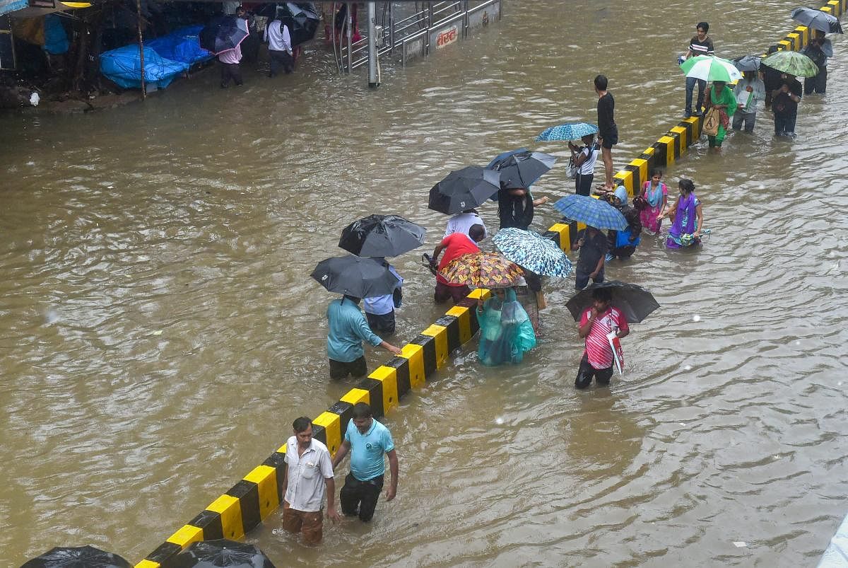 People wade through a waterlogged street following heavy rains, in Mumbai. PTI file photo