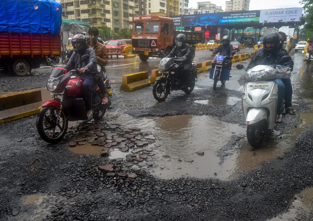 Commuters ride past pot-holes filled road after heavy rainfall, in Mumbai on Monday. (PTI file photo))