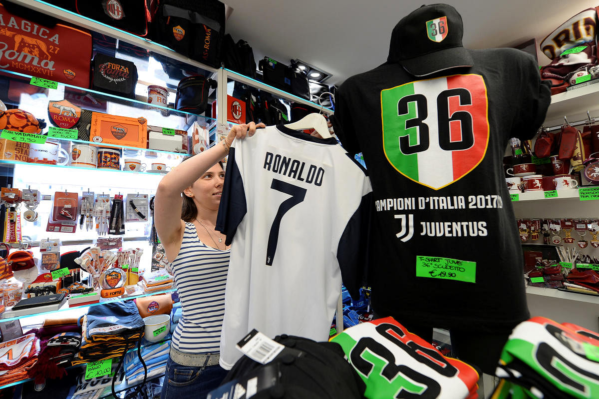 A woman adjusts a Juventus jersey with the name of Cristiano Ronaldo at a souvenir shop in Turin, Italy July 11, 2018. REUTERS