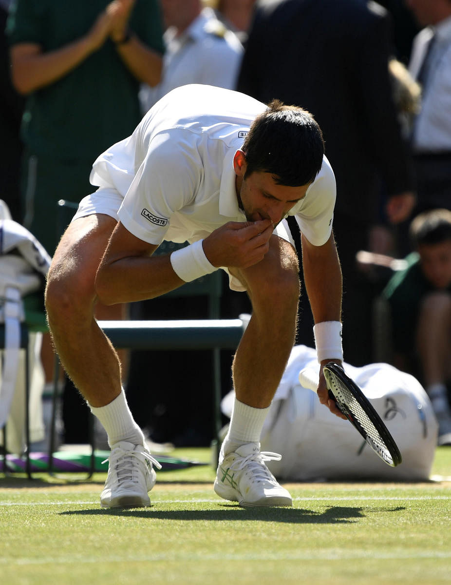 Serbia's Novak Djokovic eats grass from the court as he celebrates after winning the men's singles final against South Africa's Kevin Anderson. (REUTERS/Tony O'Brien)