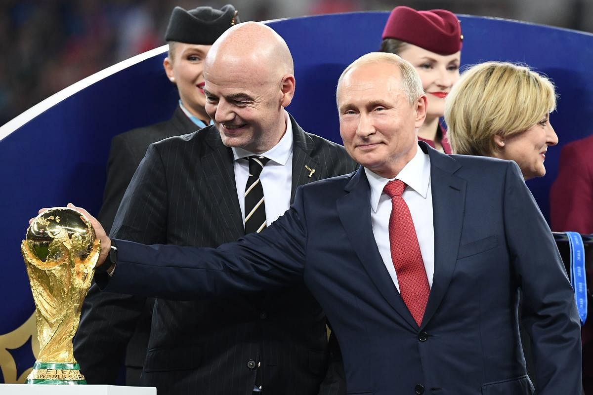 Russian president Vladimir Putin (left) touches the World Cup trophy during the post-match ceremony on Sunday. Also seen are FIFA president Gianni Infantino (left). AFP