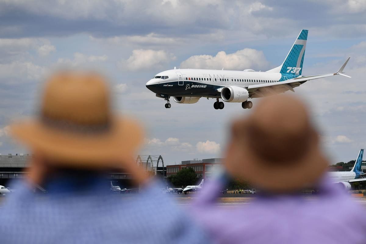 Visitors watch as a Boeing 737 Max lands after an air display during the Farnborough Airshow 2018. AFP