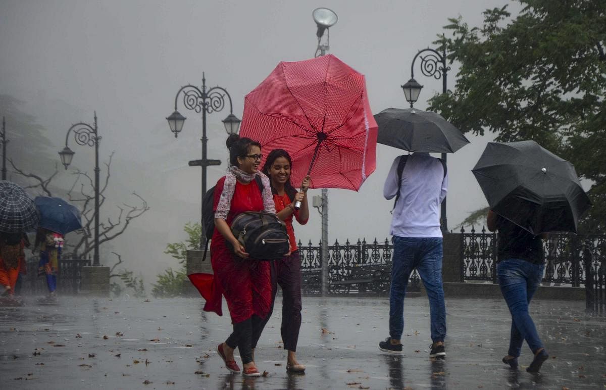 People walk under an umbrella during heavy rainfall, in Shimla. PTI photo.