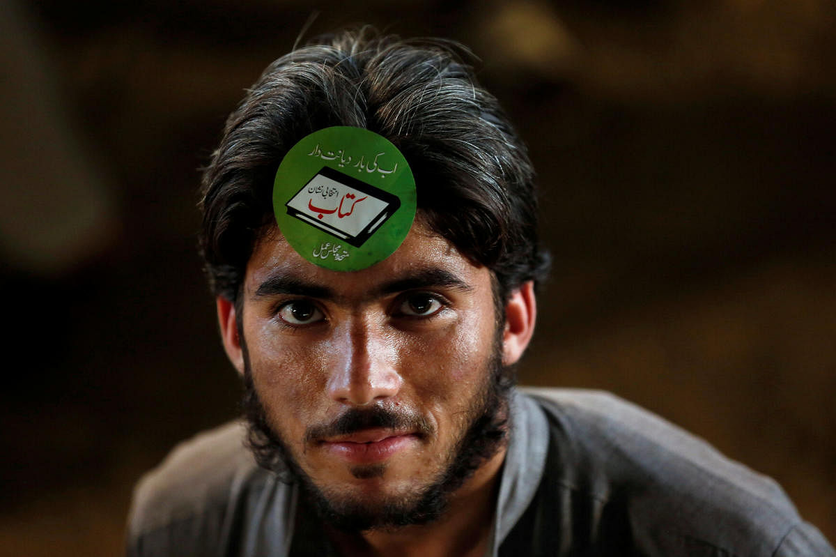 A supporter of the Muttahida Majlis-e-Amal (MMA), a coalition between religious-political parties, adorns an electoral sticker during a campaign rally, ahead of general elections in Karachi, Pakistan July 15, 2018. (REUTERS/Akhtar Soomro)