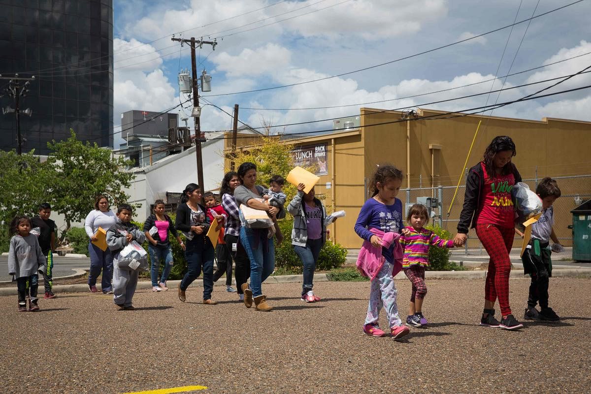 Immigrants walk to a nearby Catholic Charities relief centre after being dropped off at a bus station shortly after release from detention through "catch and release" immigration policy in McAllen, Texas. AFP file photo