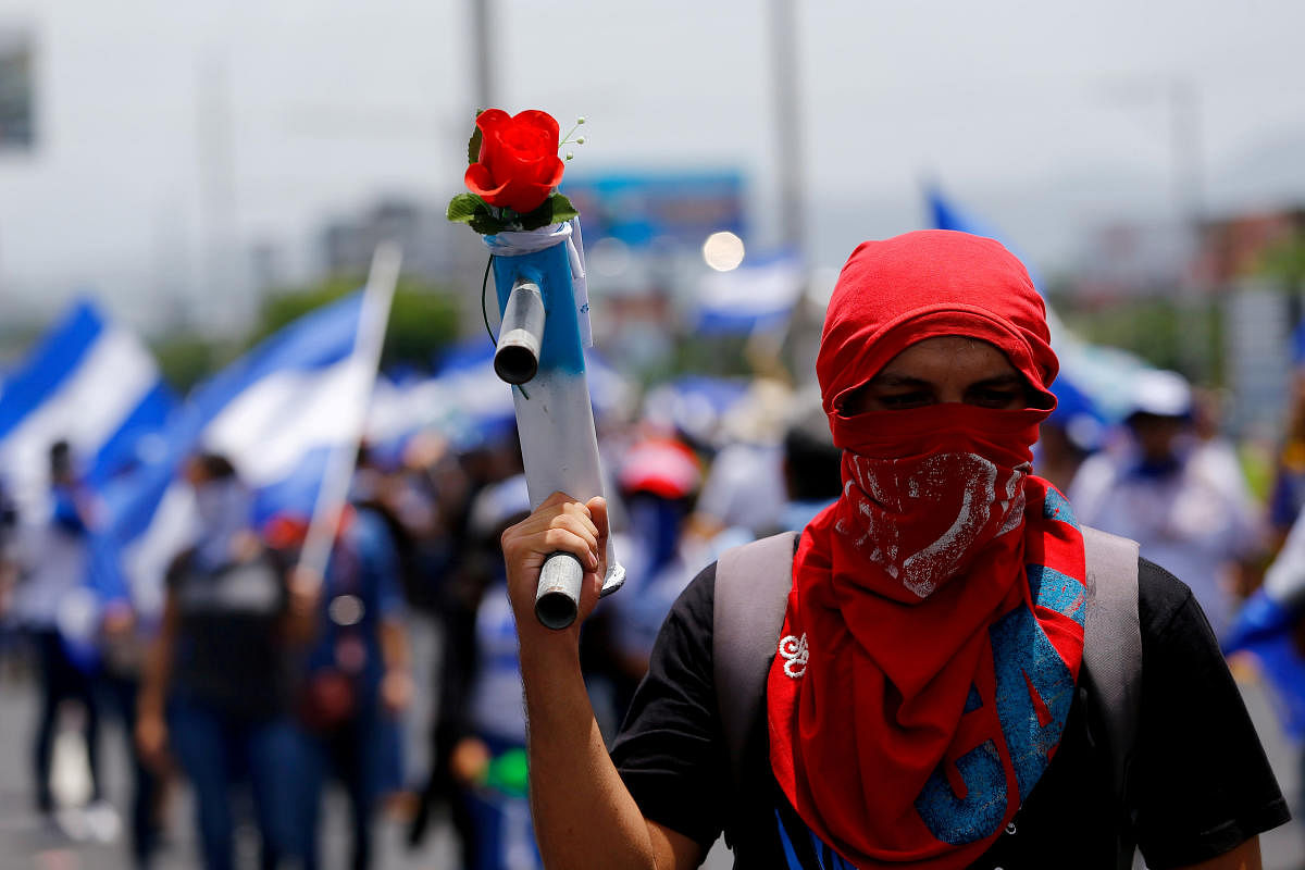 A masked demonstrator holds a homemade mortar with a flower during a march to demand the release of the political prisoners arrested during recent protests against Nicaragua's President Daniel Ortega's government in Managua, Nicaragua July 21, 2018. Reuters