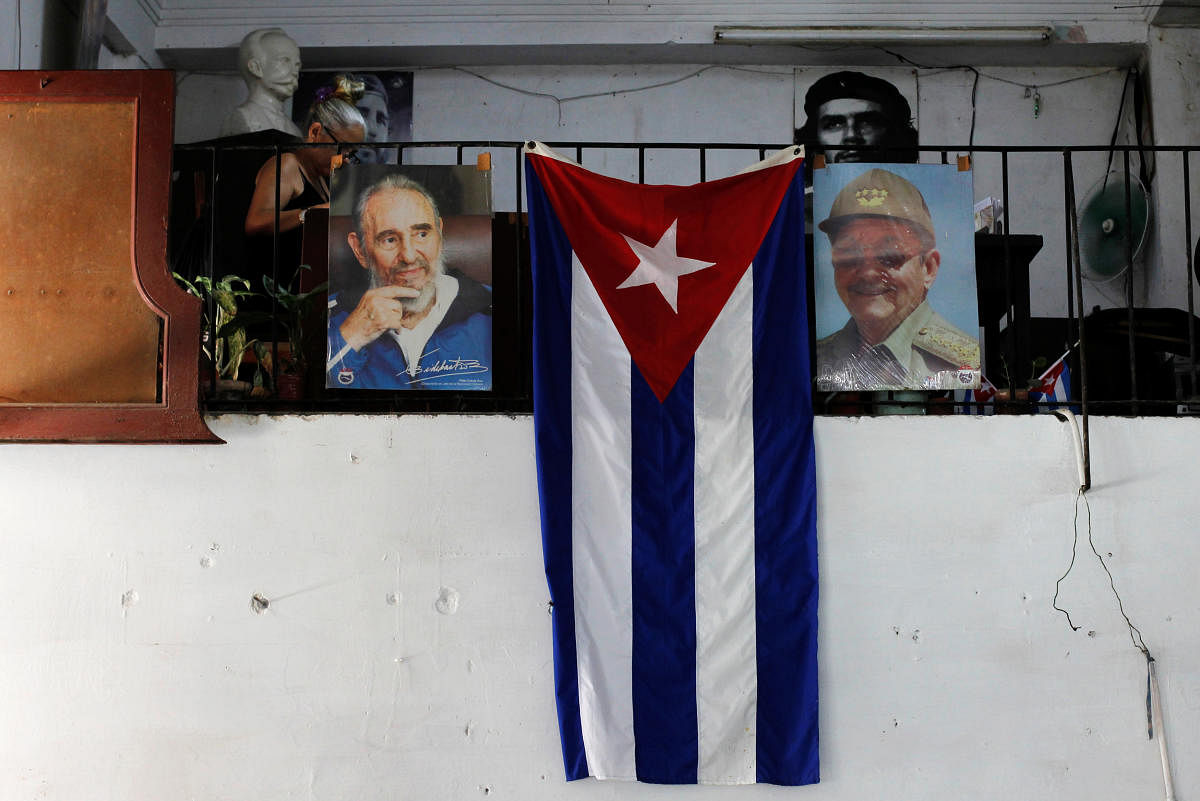 The Cuban flag hangs next to the photographs of late Cuba's President Fidel Castro and his brother, Cuba's former President Raul Castro, in Havana. REUTERS.