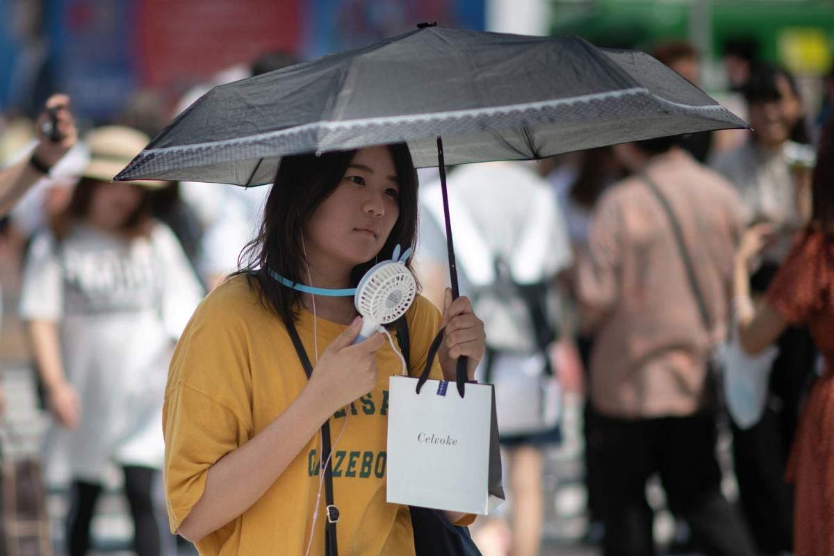 A woman uses a portable fan to cool herself in Tokyo on July 24, 2018. The weather agency has classified the record-breaking weather as a "natural disaster." (AFP Photo)