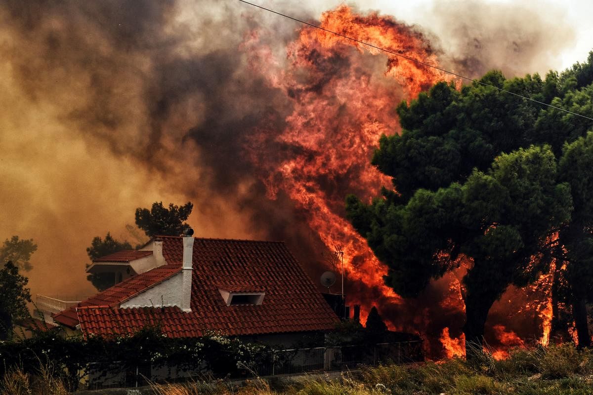 A house is threatened by a huge blaze during a wildfire in Kineta, near Athens, on July 23, 2018. (AFP Photo)