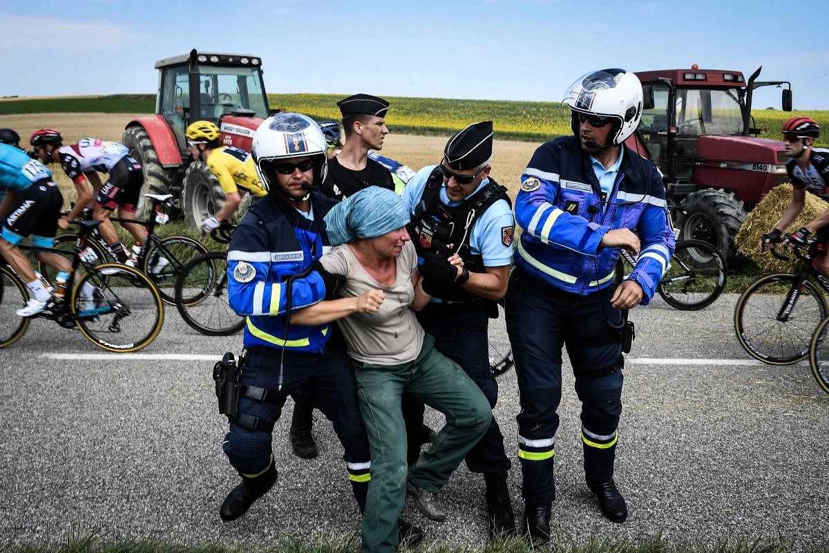 Gendarmes (French paramilitary officers) detain a protester during the 16th stage of the Tour de France cycling on Tuesday. AFP 