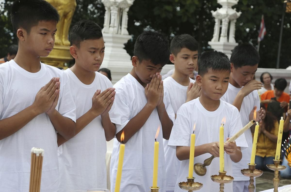 Chanin Vibulrungruang lights a candle with members of the rescued soccer team during a Buddhist ceremony that is believed to extend the lives of its attendees as well as ridding them of dangers and misfortunes, in Mae Sai district, Chiang Rai province, no