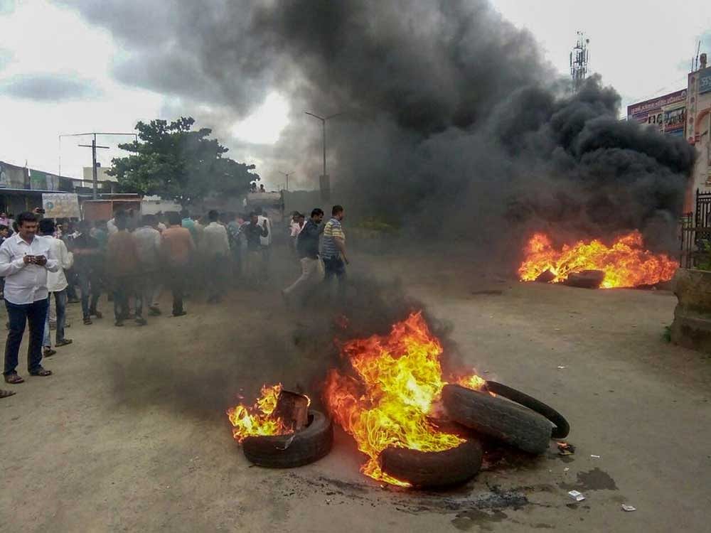 Smoke billows from a burning tyre during a protest rally demanding reservation for Marathis, at Neknoor village in Beed district on Tuesday, July 24, 2018. Maratha outfits have called for a bandh in Maharashtra a day after of a protestor demanding reservation for the community jumped off a bridge over Godavari river and died, in Aurangabad. PTI Photo