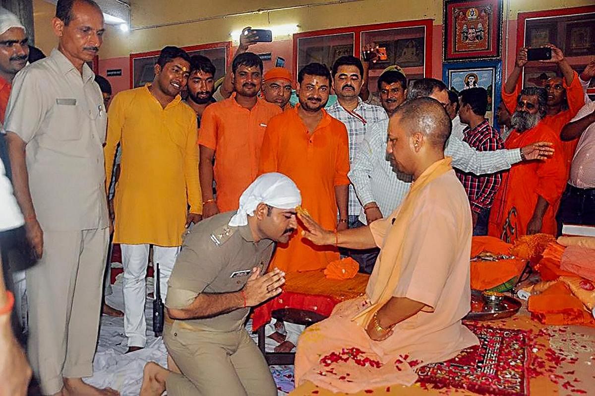 A police officer in uniform kneels down at the feet of Uttar Pradesh Chief Minister Yogi Adityanath, on the occasion of Guru Purnima at the Gorakhnath temple, in Gorakhnath on Friday. Adityanath is also head priest of the Gorakhnath Math. PTI