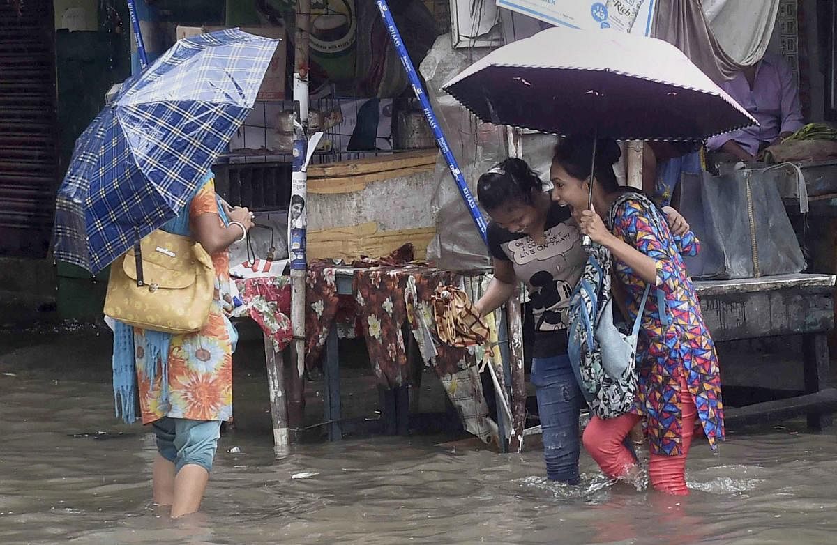 People walk cautiously on a flooded road after heavy rains in Kolkata. (PTI Photo)