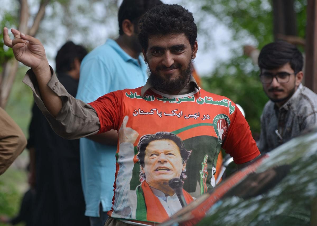 A supporter of Pakistan's cricketer-turned politician Imran Khan, and head of the Pakistan Tehreek-e-Insaf (Movement for Justice) party, gestures as he wears a t-shirt featuring an image of Khan's near his residence in Islamabad on July 26, 2018, a day af