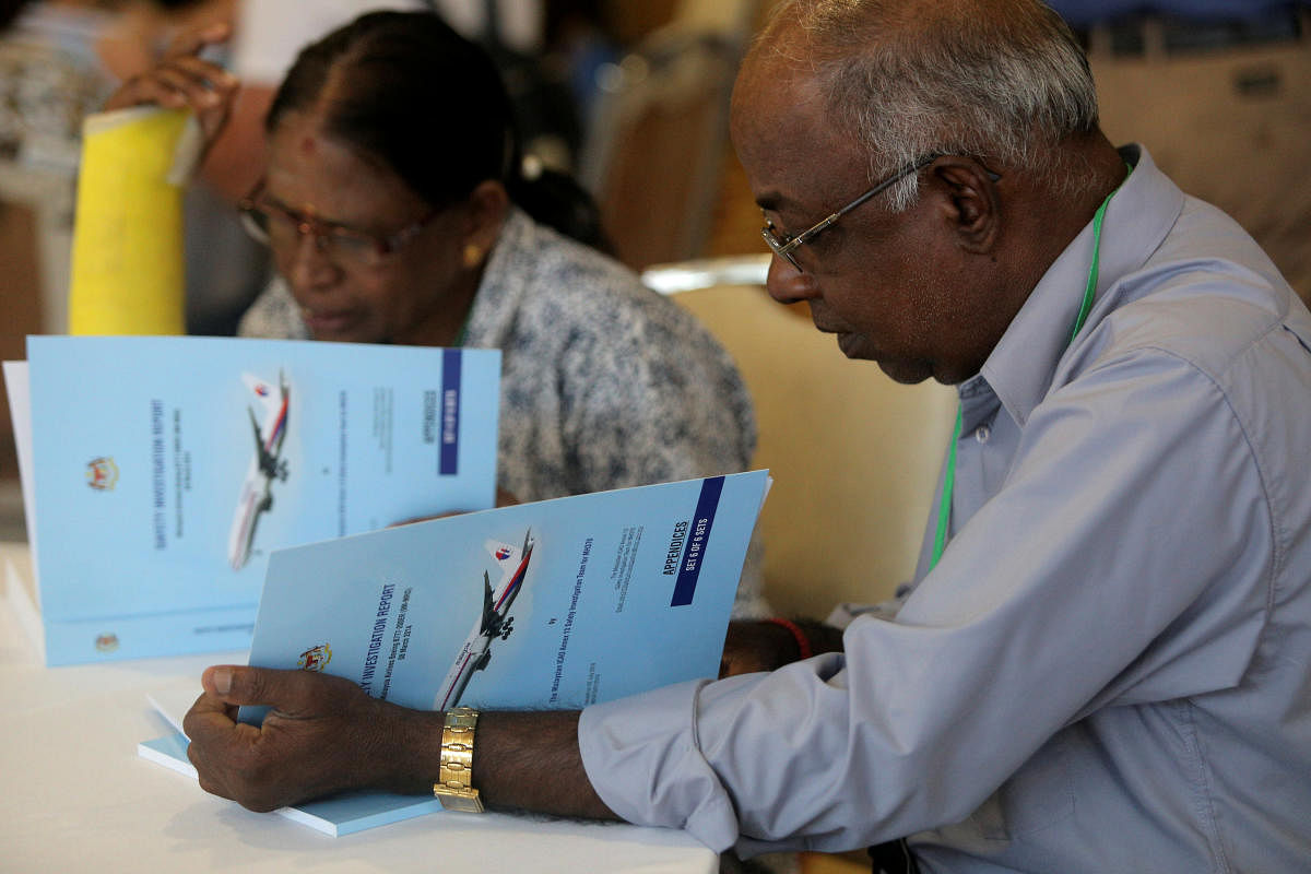 Family members read MH370 briefing reports before a closed door meeting in Putrajaya, Malaysia, on Monday. Reuters